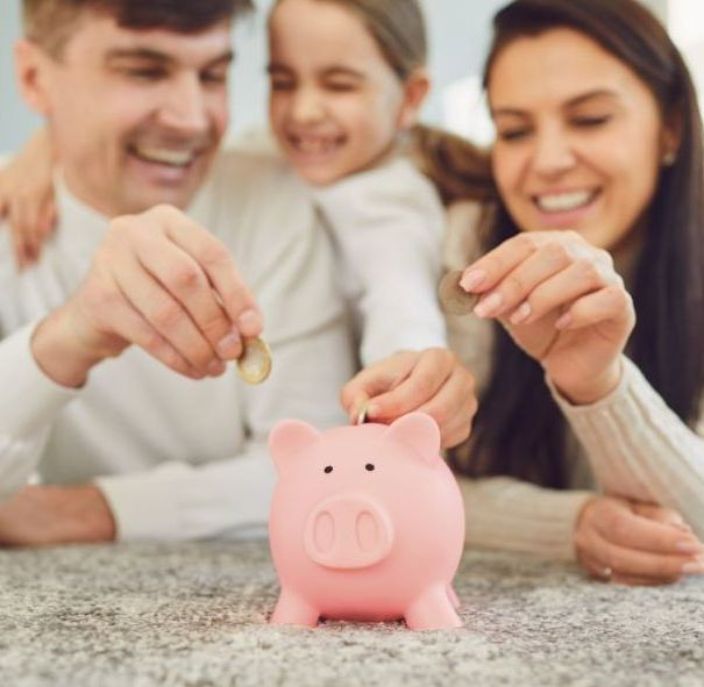 Eltern mit Kind sparen mit dem Sozialtarif und stecken Münzen in ein Sparschwein